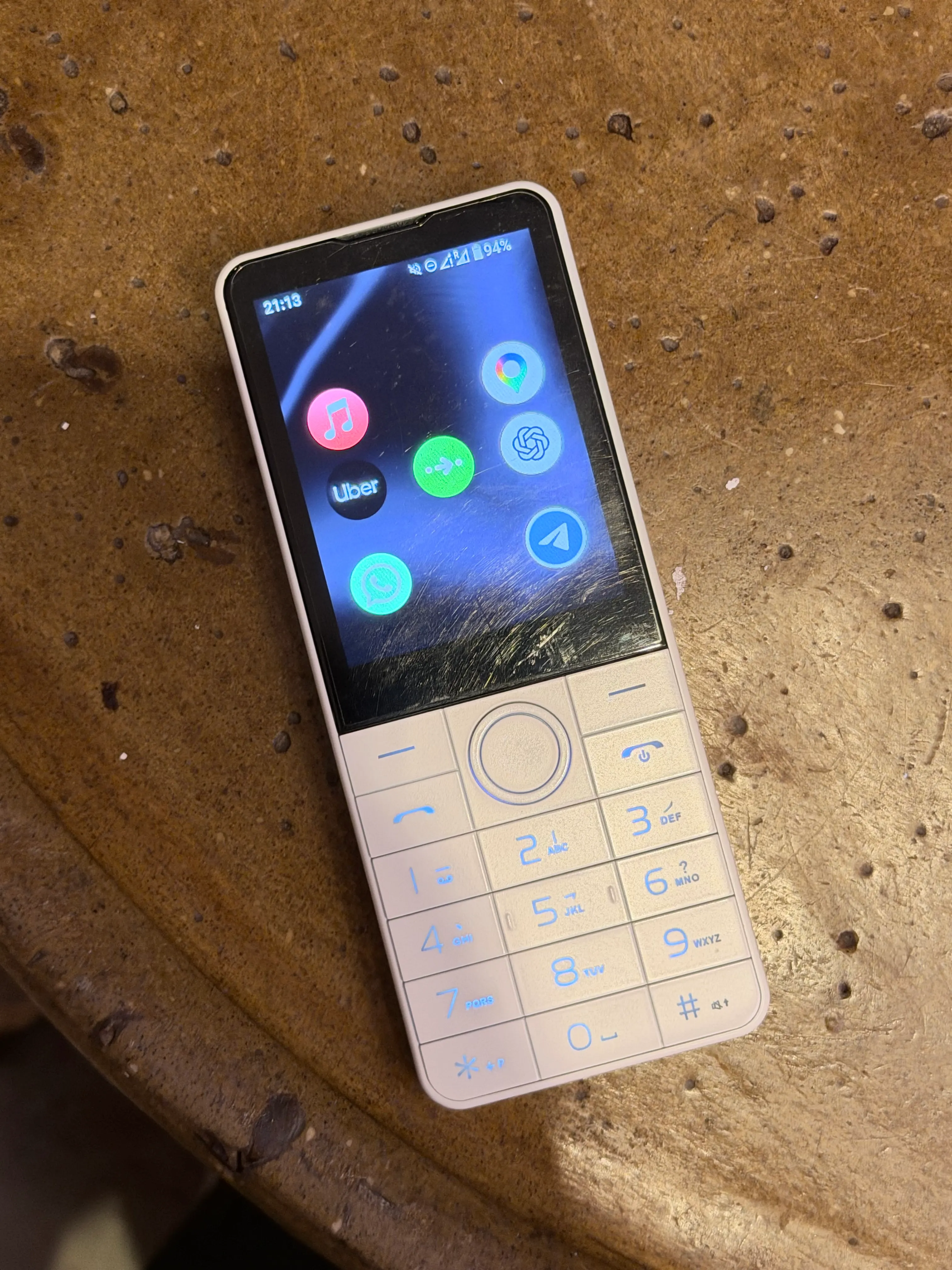 Doov R77 on a table, showing its home screen and illuminated numeric keypad.